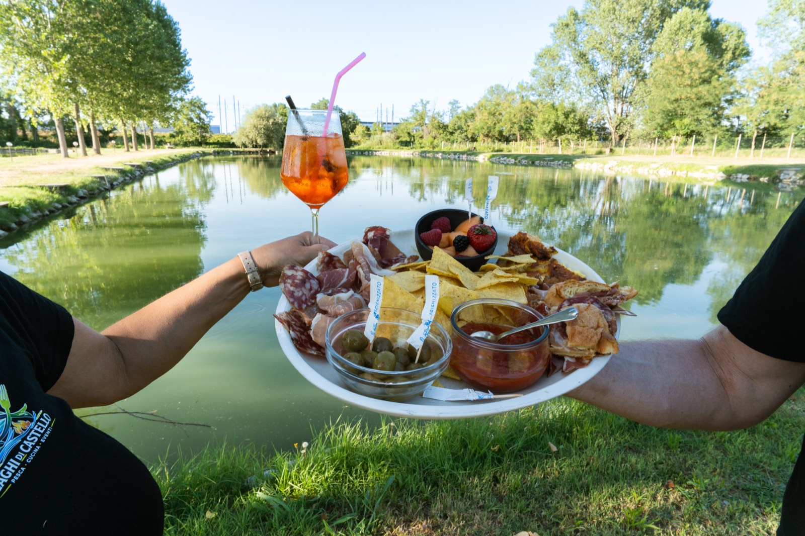 Aperitivo in riva al lago: spritz e tagliere di salumi con l'acqua sullo sfondo
